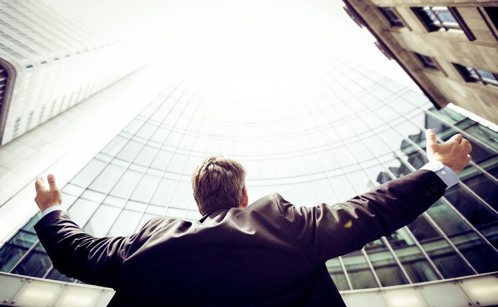 Person with arms wide open in front of buildings